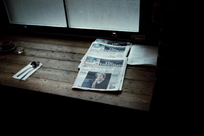 Stak af papiraviser ved et vindue i køligt dagslys