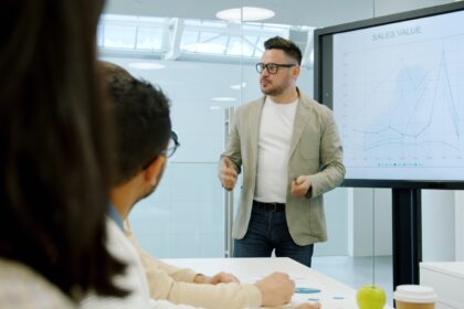 Oplægsholder præsenterer data på storskærm for kolleger under et lokalt erhvervsseminar
