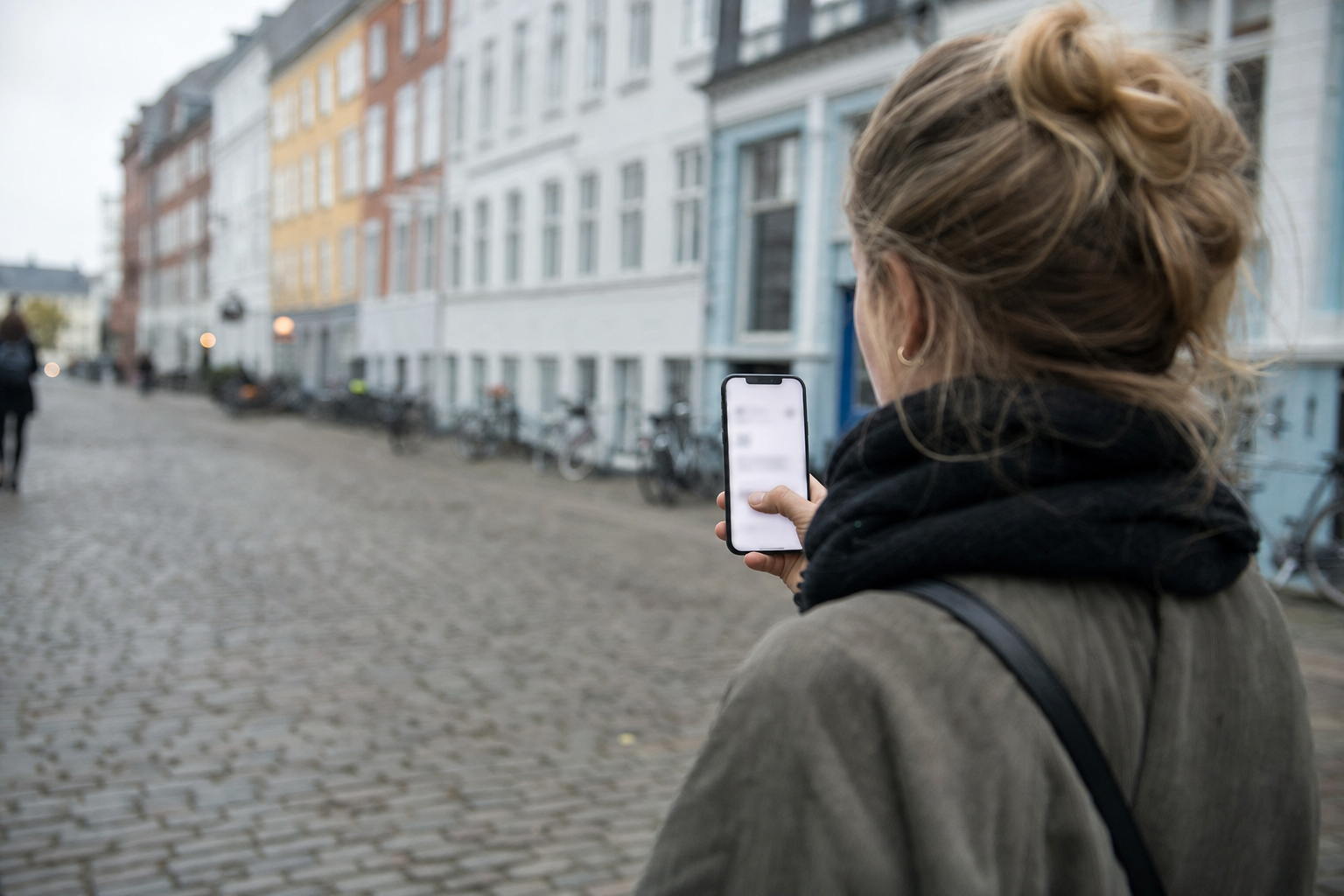 Kvinde går gennem en gade med telefonen i hånden på vej til en adresse