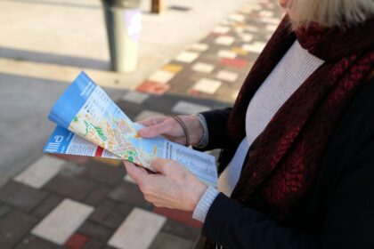 Kvinde står udendørs og studerer et udfoldet papirkort
